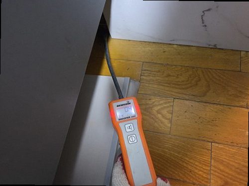 군포 누수탐지 거실 벽면 누수 흔적과 수분 측정기를 확인하는 모습
